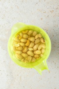 in Wasser eingeweichte Cashewn&uuml;sse in einem gr&uuml;nen Messbecher