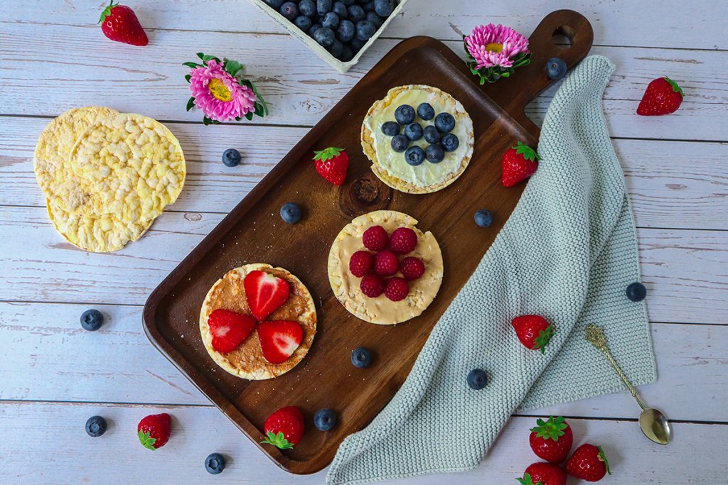 Maiswaffeln mit Nussmus und Fr&uuml;chten belegt als gesunder Snack mit gesunden Lebensmitteln aus der Vorratskammer.