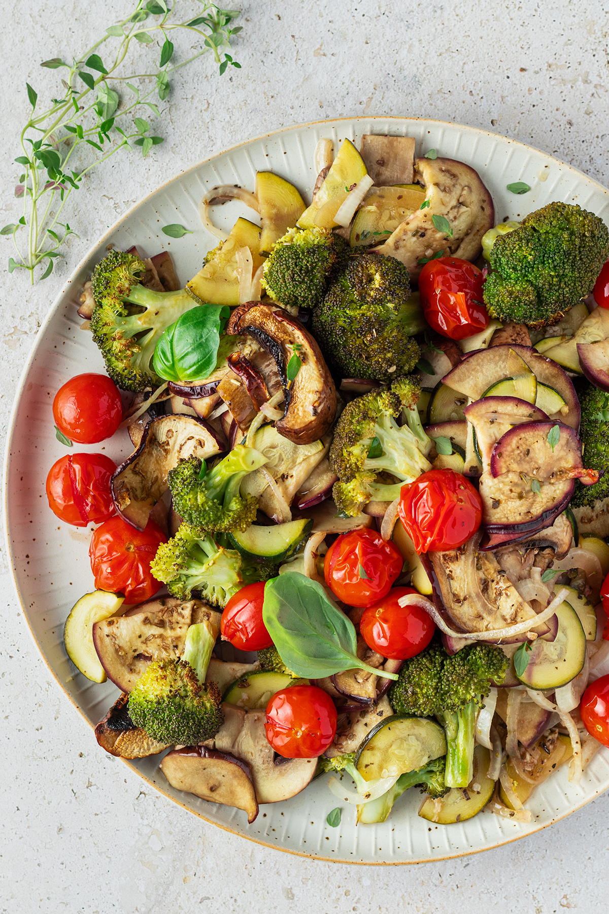 Buntes Ofengem&uuml;se vom Blech mit Tomaten, Brokkoli, Aubergine und Zucchini serviert auf einem gro&szlig;en, wei&szlig;en Teller.