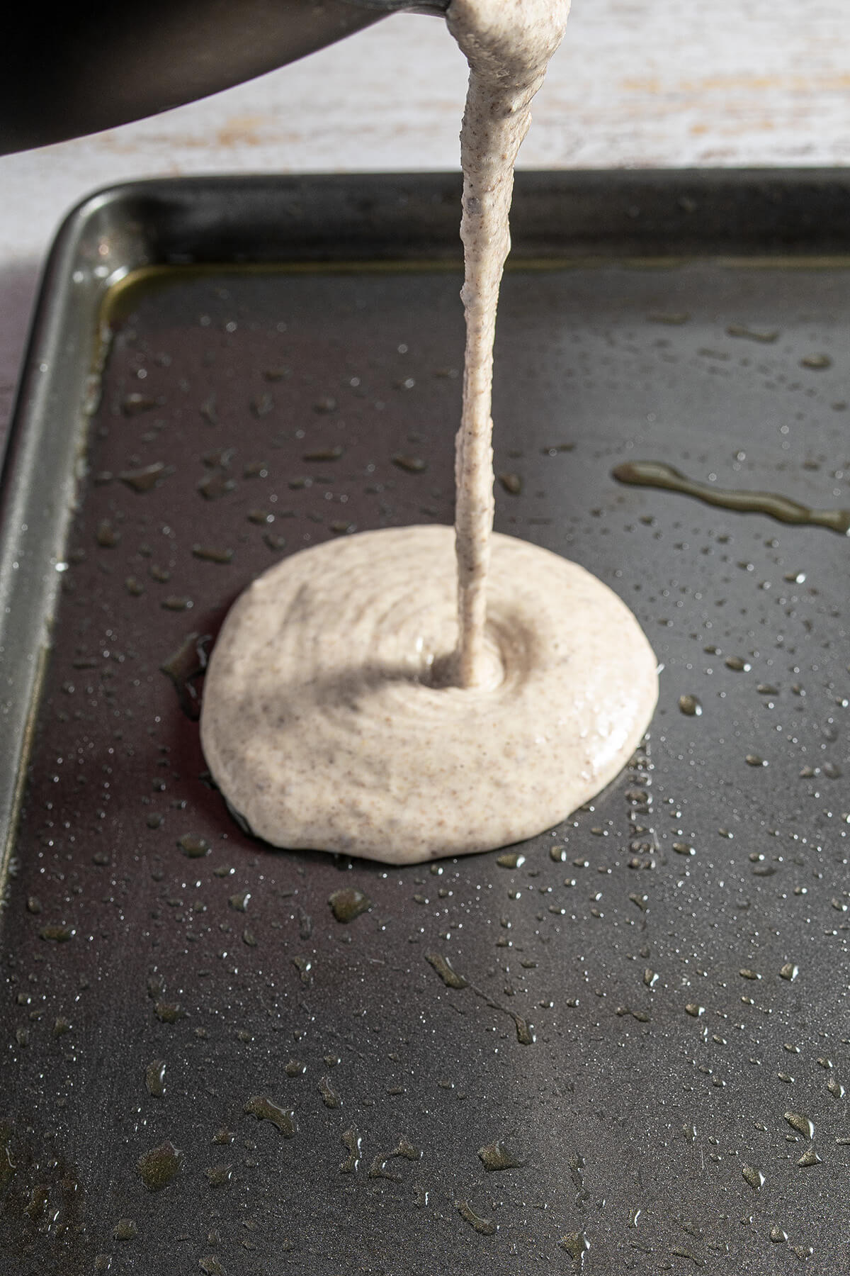 Pfannkuchenteig auf die Mitte des ausgefetteten Blechs gegossen.