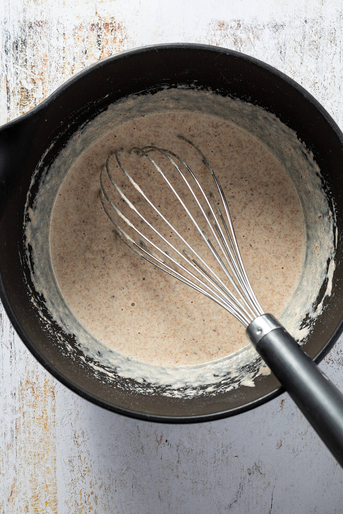 Pfannkuchenteig wird mit einem Schneebesen in eine Sch&uuml;ssel verr&uuml;hrt.