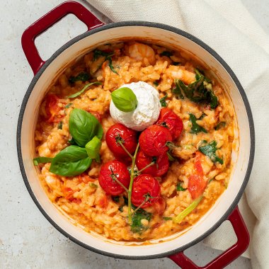 Ofenrisotto mit Tomaten, Ricotta, Spinat und Garnelen in einem Schmortopf serviert