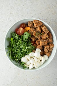 ger&ouml;stete Brotw&uuml;rfel, Mozzarella, Rucola und halbierte Cherrytomaten in einer Salatsch&uuml;ssel