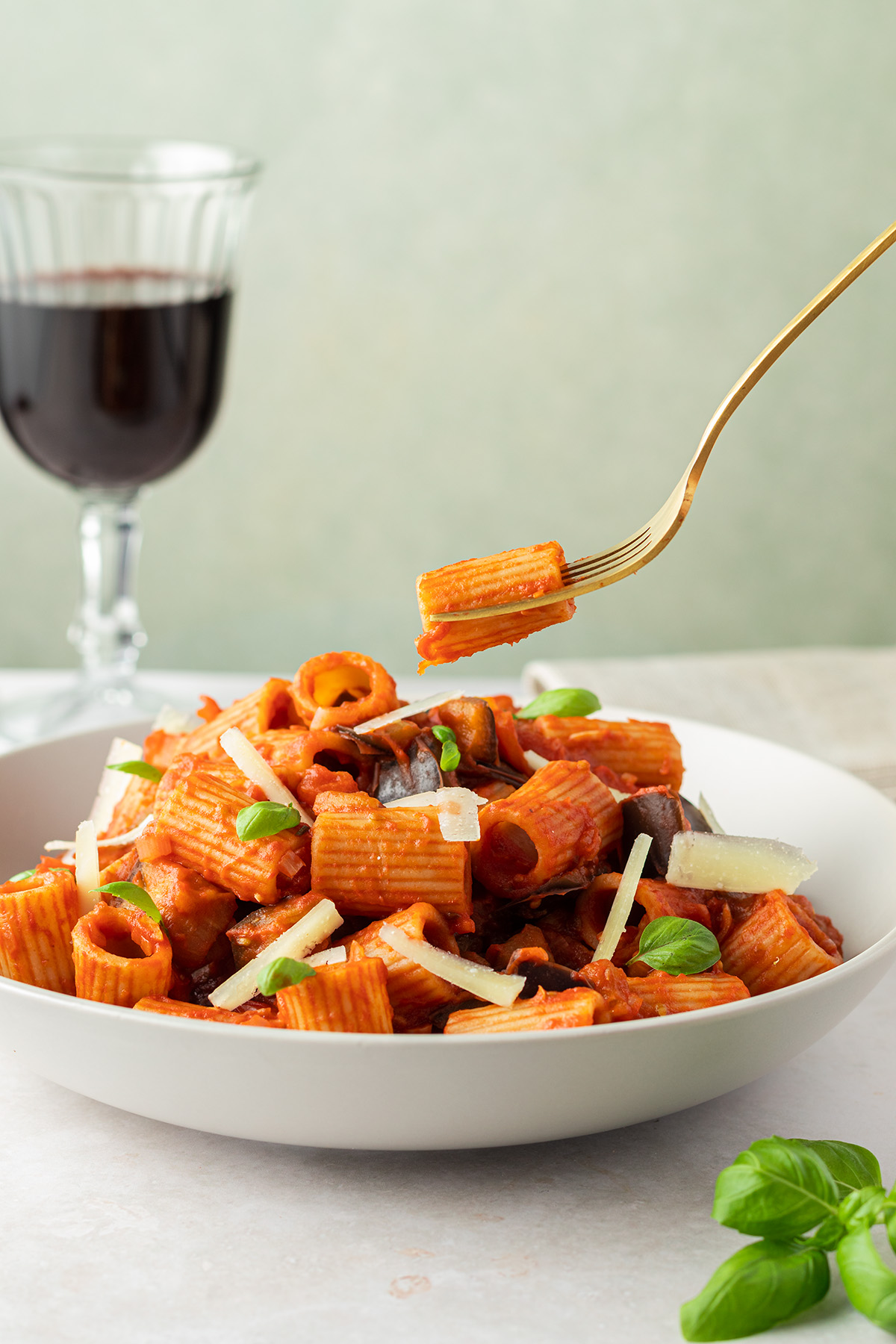 von einem Teller mit Pasta mit Auberginen Tomatensauce wird eine Gabel weggenommen