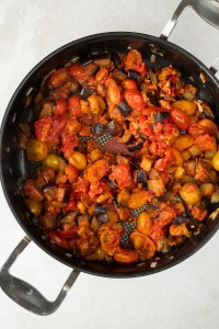 gebratene Auberginen-, Schalotten- und Knoblauchwürfel mit Tomatenmark in einer großen Pfanne
