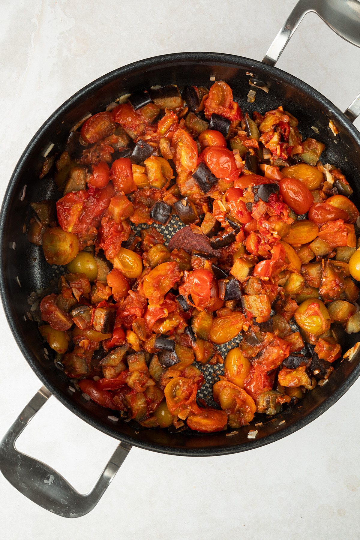gebratene Auberginen-, Schalotten- und Knoblauchwürfel mit Tomatenmark in einer großen Pfanne
