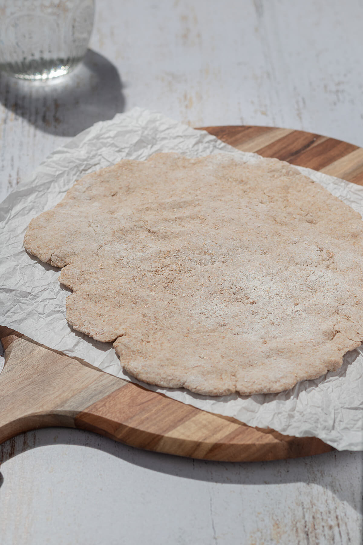 Halbwegs rund geformter Pizzateig auf einem Brett.