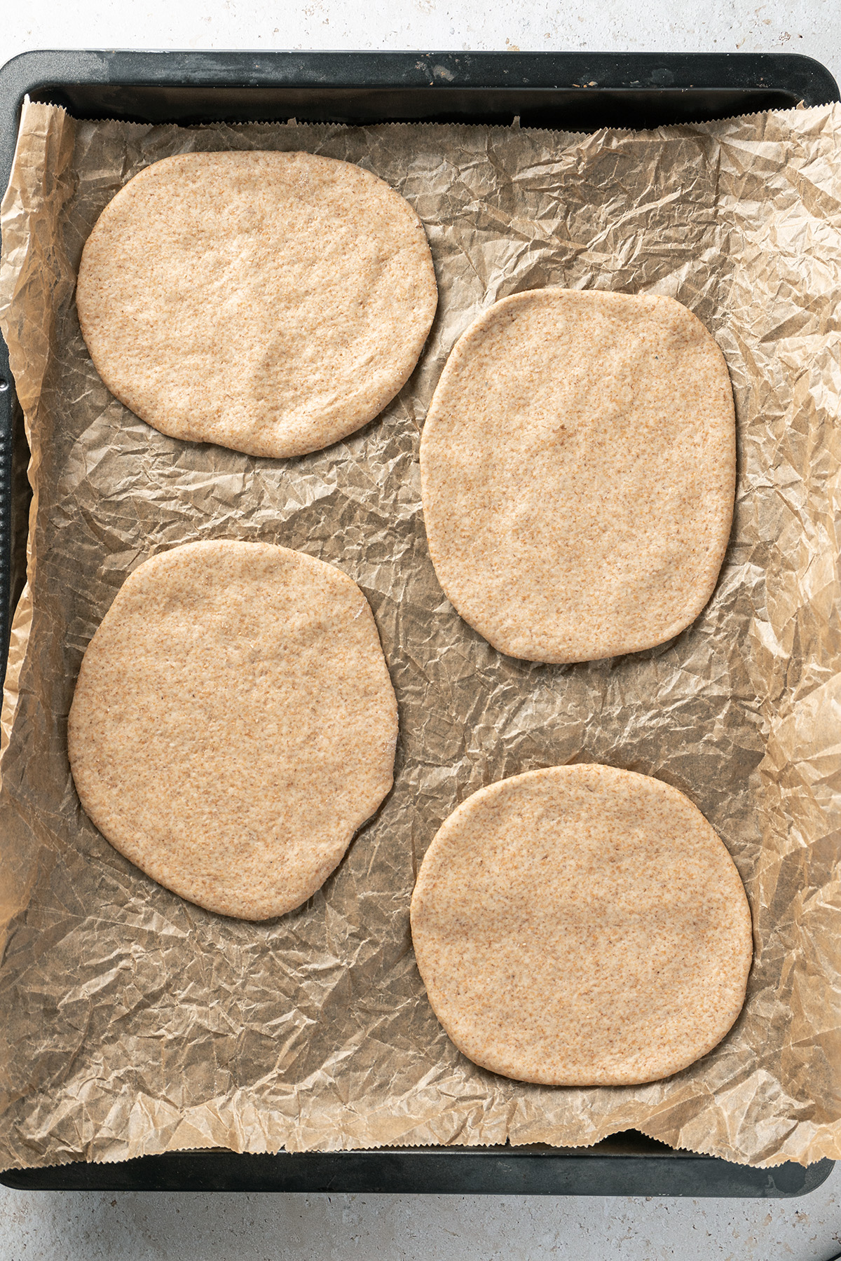 Pita Brot Fladen ausgerollt auf einem mit Backpapier ausgelegtem Blech