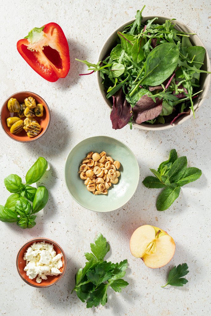 Zutaten nach dem Salatbaukasten-Prinzip: Dunkle Salatbl&auml;tter, eine halbe Paprika, Oliven, N&uuml;ssen, frische Kr&auml;uter, ein halber Apfel und Feta