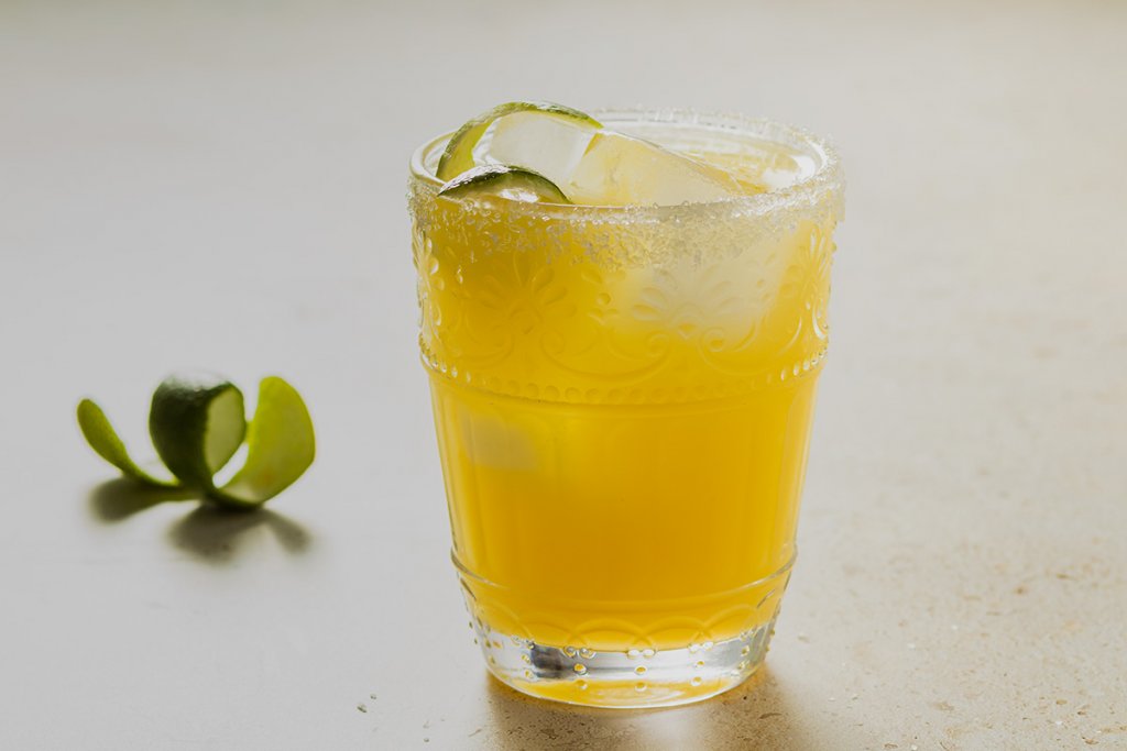 Kalorienarmer Cocktail mit Tequila, Orangen- und Limettensaft, serviert mit einer Limettenschale