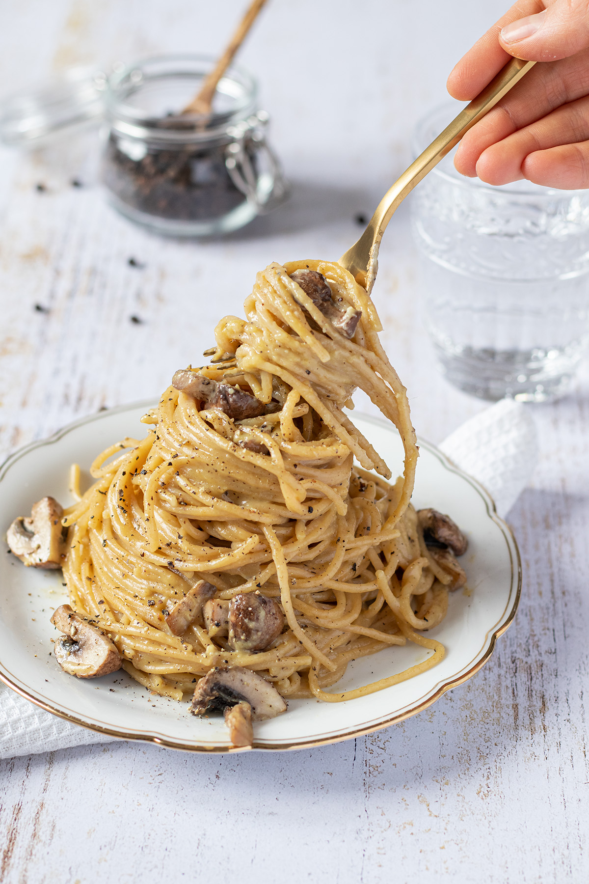 Ein Berg Spaghetti Carbonara auf einem Teller, wo gerade ein Bissen auf eine Gabel aufgedreht wird.