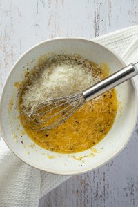 Eier und K&auml;se werden in einer kleinen Sch&uuml;ssel verquirlt.