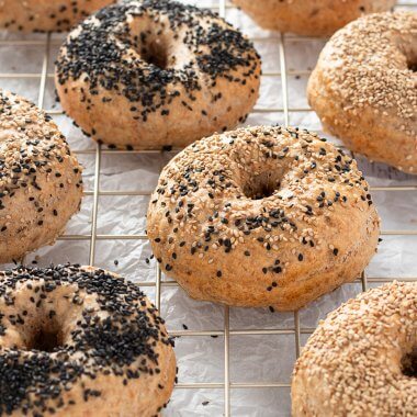 Mehrere Vollkorn Bagel mit Mohn und Sesam auf einem Abk&uuml;hlgitter.