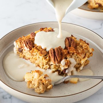 Auf ein St&uuml;ck Apfel Baked Oatmeal wird Vanillesauce gegossen.