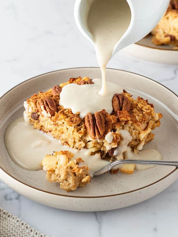 Auf ein St&uuml;ck Apfel Baked Oatmeal wird Vanillesauce gegossen.