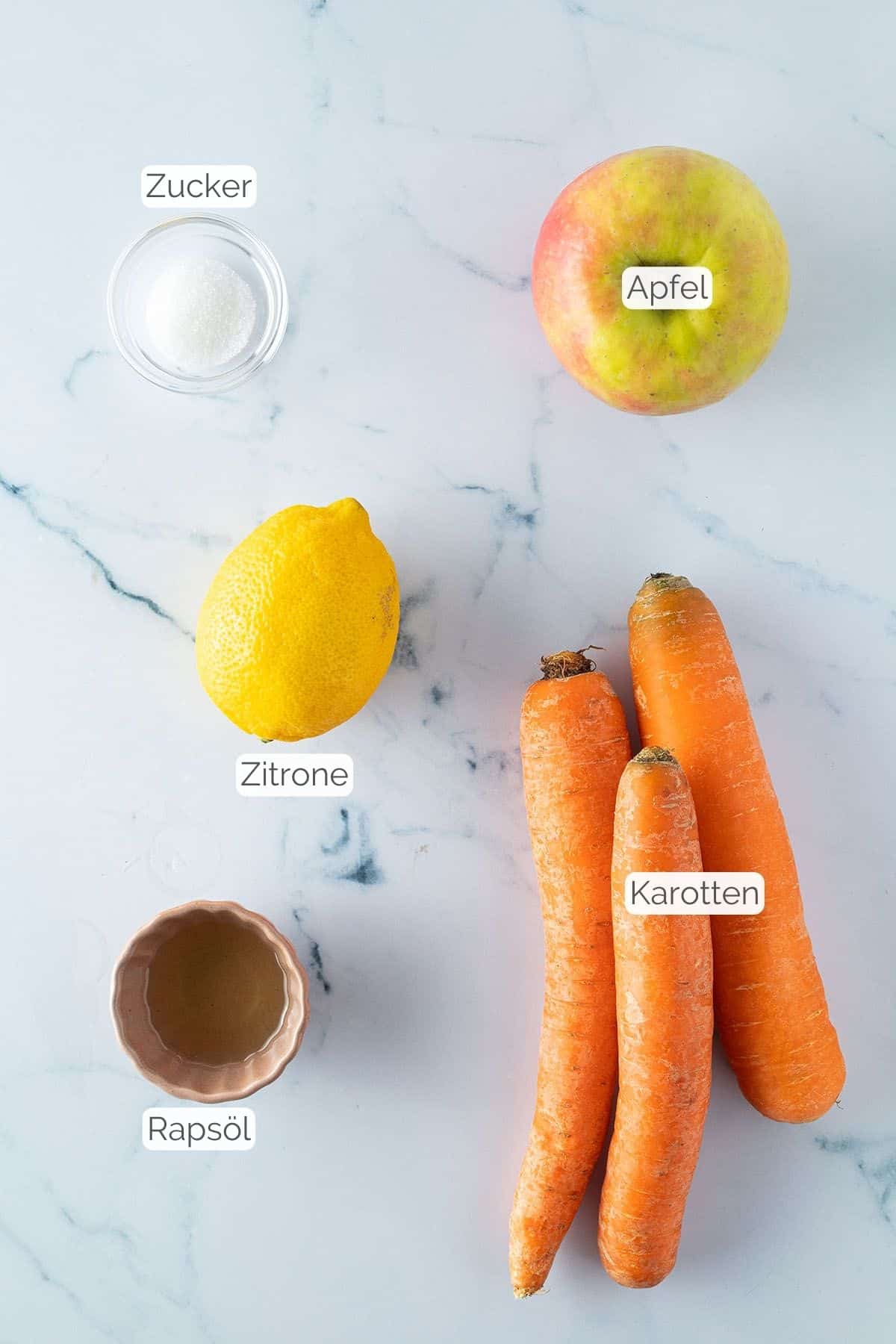 Alle Zutaten mit jeweiligen Textbeschriftungen, die für den Apfel-Möhren-Salat benötigt werden.