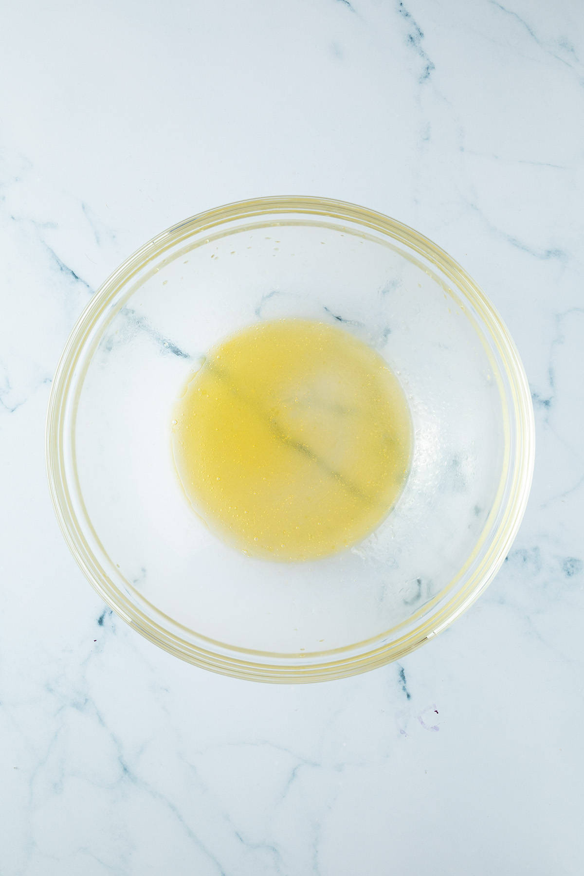Verrührtes, hellgelbes Dressing in einer Glasschüssel.
