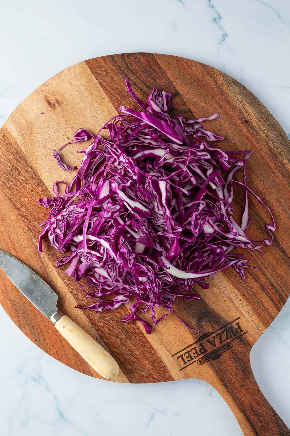In dünne Streifen geschnittener Rotkohl auf einem Brett.