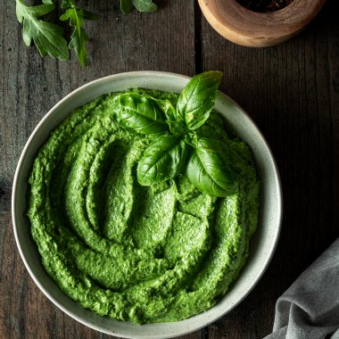 Cremige Avocado Pesto mit Deko auf einem Holztisch.