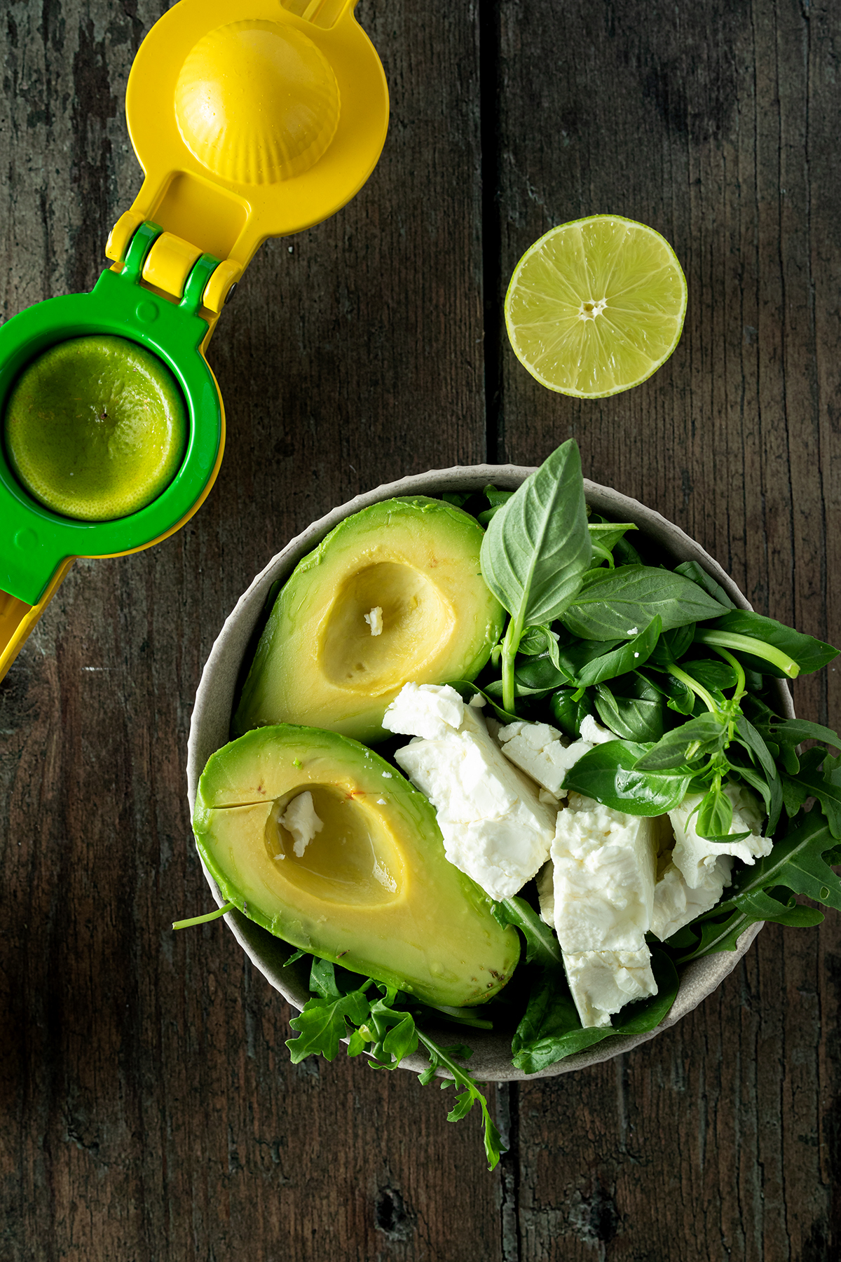 Zutaten f&uuml;r die Avocado Pesto in einer Sch&uuml;ssel, daneben eine Zitruspresse und eine Limette.