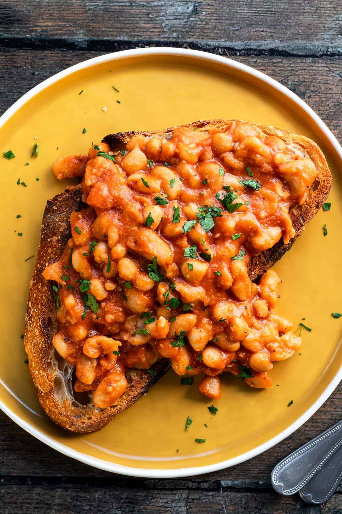 Baked Beans auf einer Scheibe Brot mit frischer Petersilie.