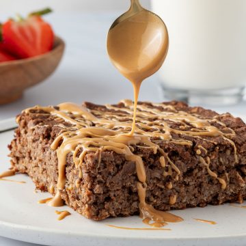 Eine Portion des Baked Oatmeals wird mit Nussmus betr&auml;ufelt.