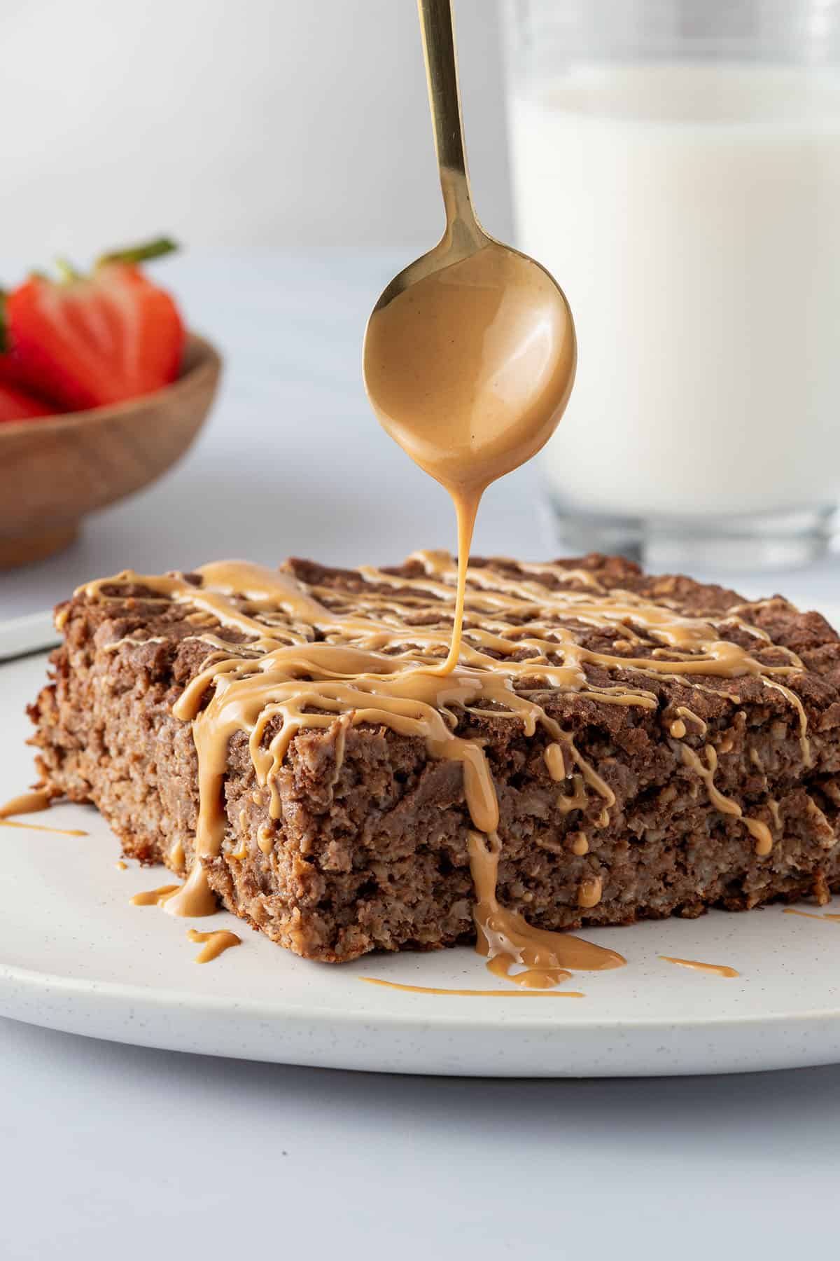 Eine Portion des Baked Oatmeals wird mit Nussmus betr&auml;ufelt.