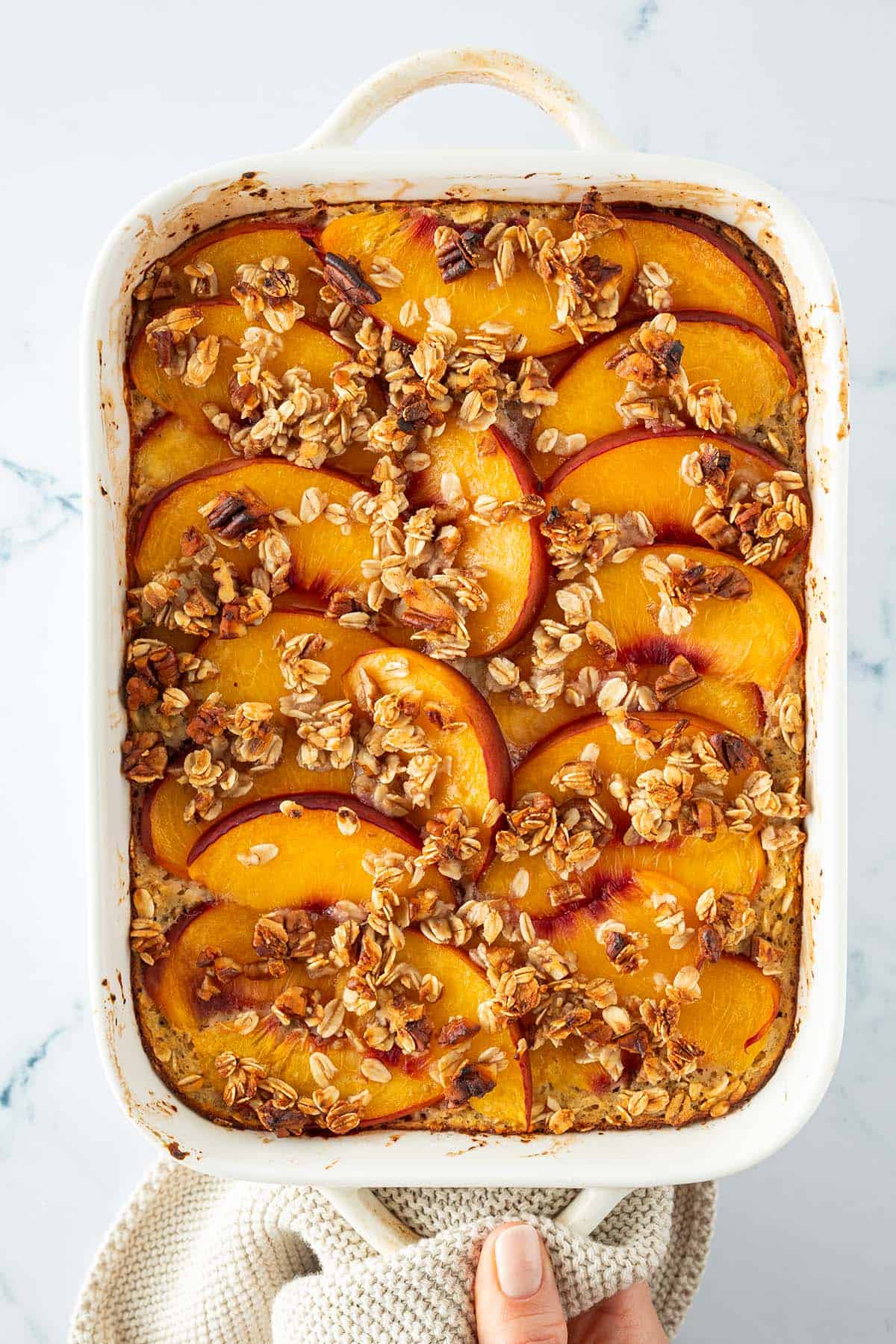 Fertig gebackene Pfirsich Baked Oats mit goldbraunen Haferflocken Streusel und weichen, saftigen Pfirsich Spalten.