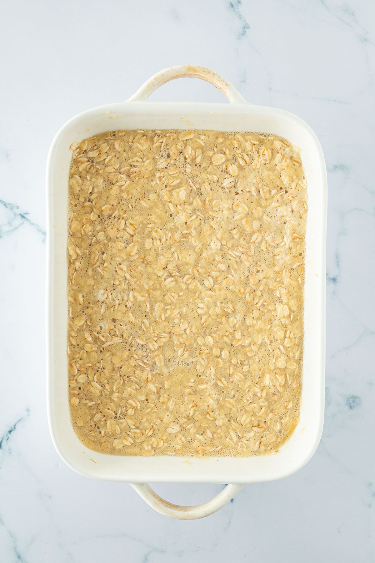Baked Oatmeal Mischung aus Haferflocken, Eier und Apfelmus in einer Auflaufform.
