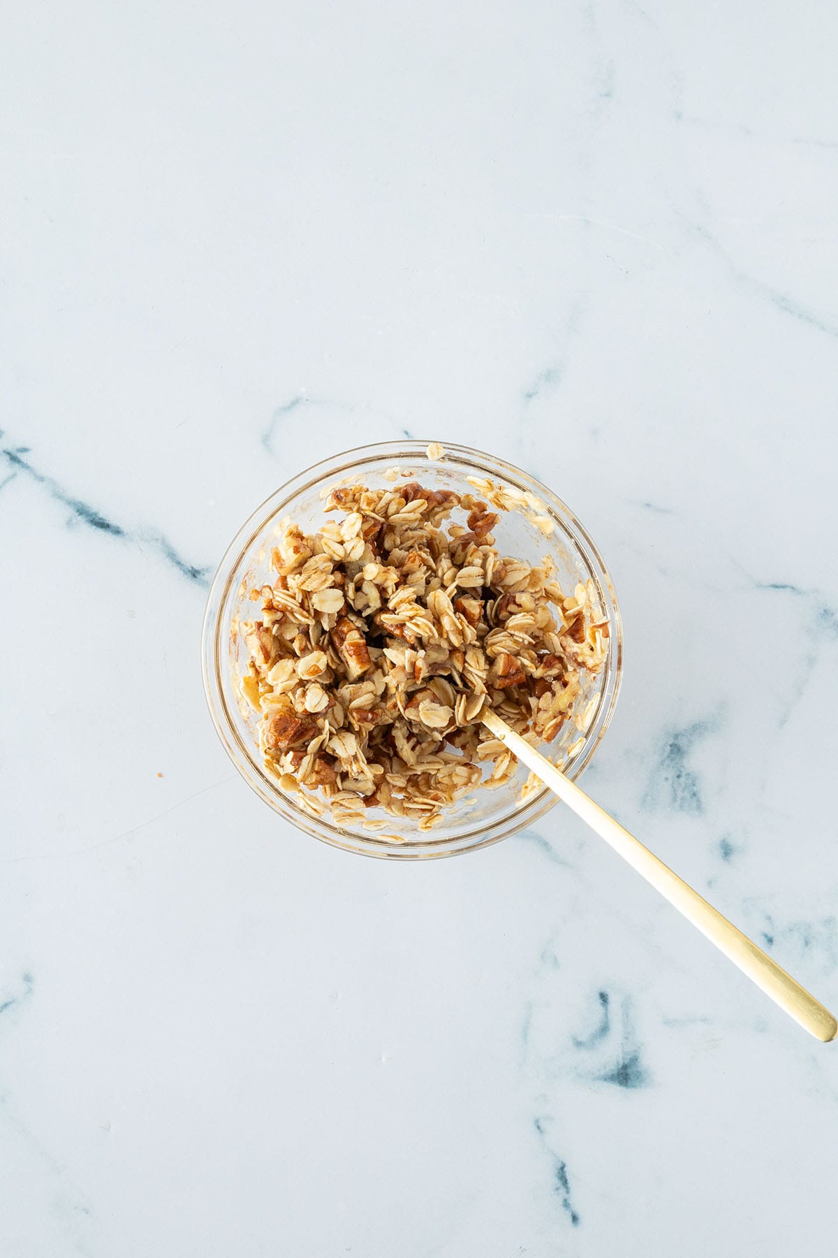 Haferflocken-Pecan-Streusel in einer kleinen Sch&uuml;ssel mit einem L&ouml;ffel verr&uuml;hrt.