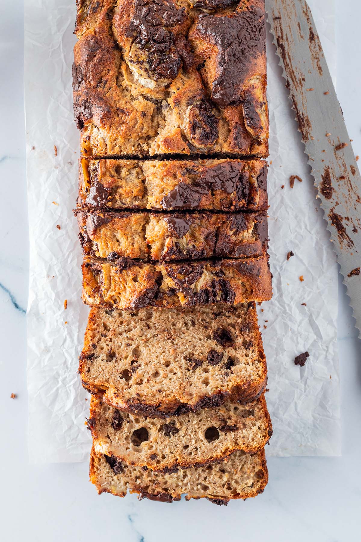 Vogelperspektive auf ein angeschnittenes Bananenbrot mit Schokost&uuml;ckchen.