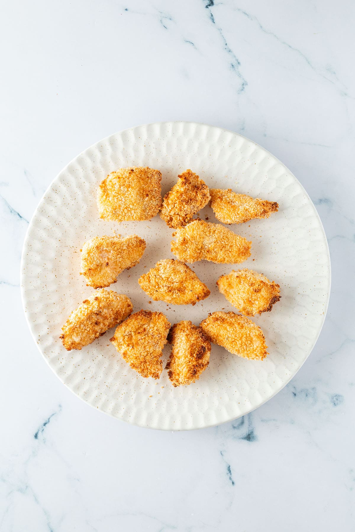 Im Airfryer goldbraun und knusprig gebackene Bang Bang Chicken St&uuml;cke auf einem Teller.