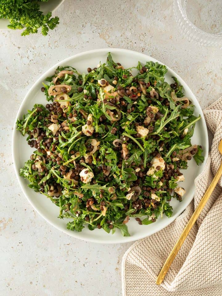 Beluga Linsensalat mit Feta, Kr&auml;uter und Rucola auf einem Teller.