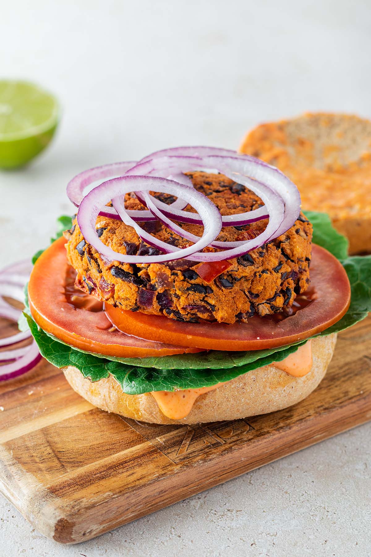 Bohnenbratling auf einem Burgerbr&ouml;tchen mit frischem Salat, Tomatenscheiben und Zwiebelringen.