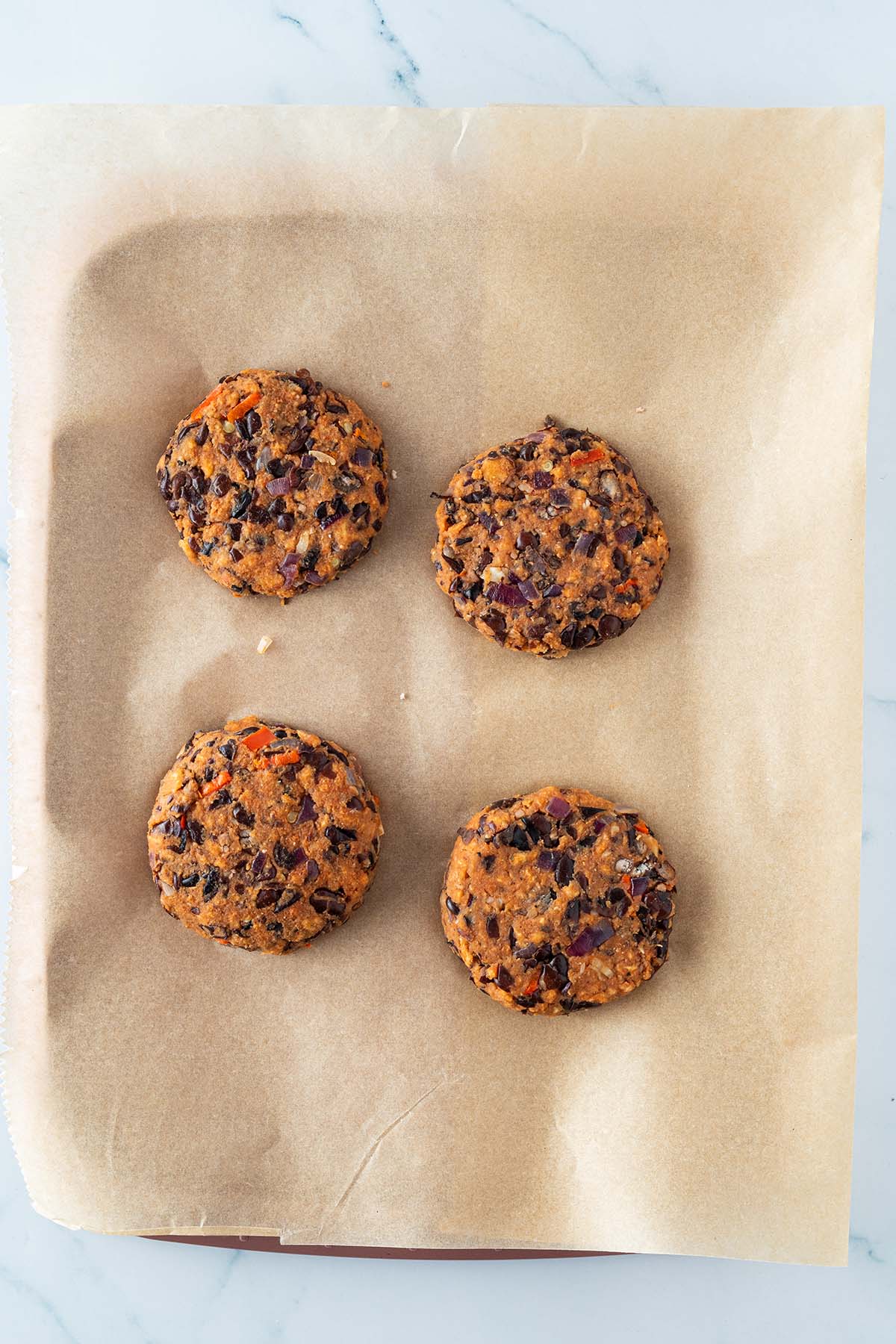 Bohnenmasse wurde zu vier Patties geformt und auf ein Bleh mit Backpapier gelegt.