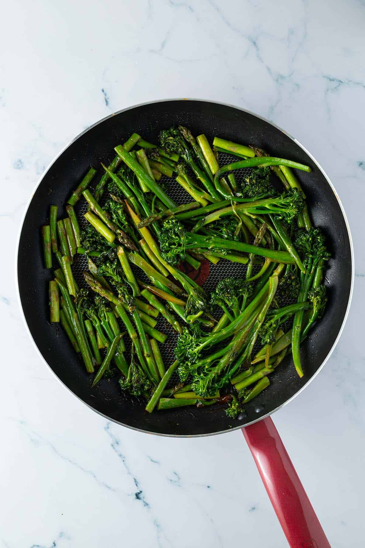 Gebratener Brokkoli und Spargel in einer Pfanne.