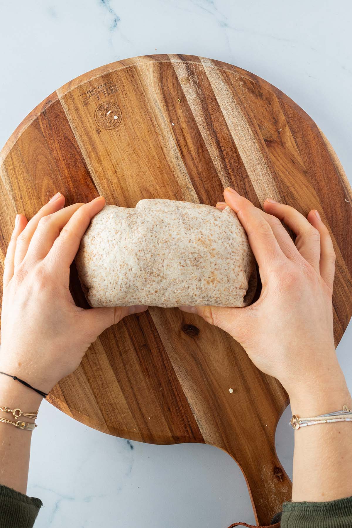 Ein fertig gerollter Burrito wird von zwei H&auml;nden gehalten.
