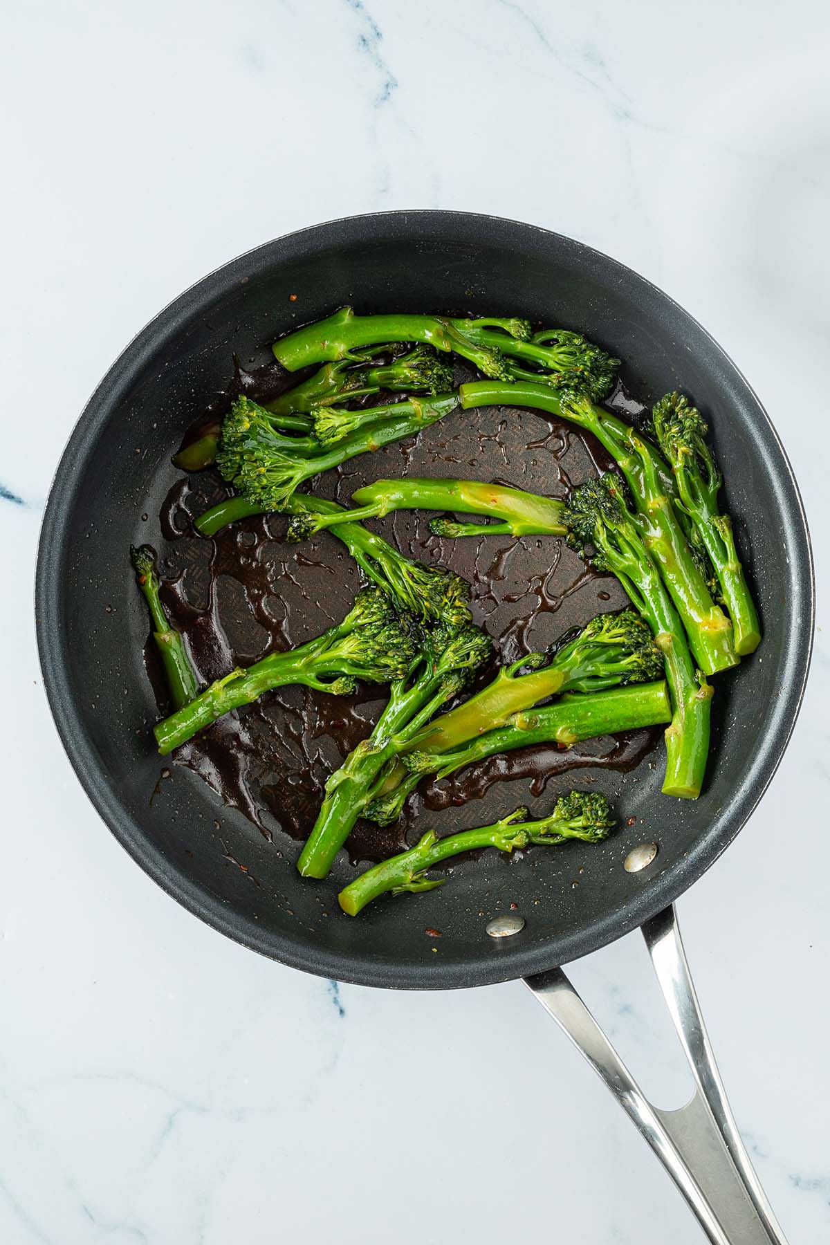 Ged&auml;mpfter Brokkoli mit einer asiatischen Sauce in einer Pfanne.