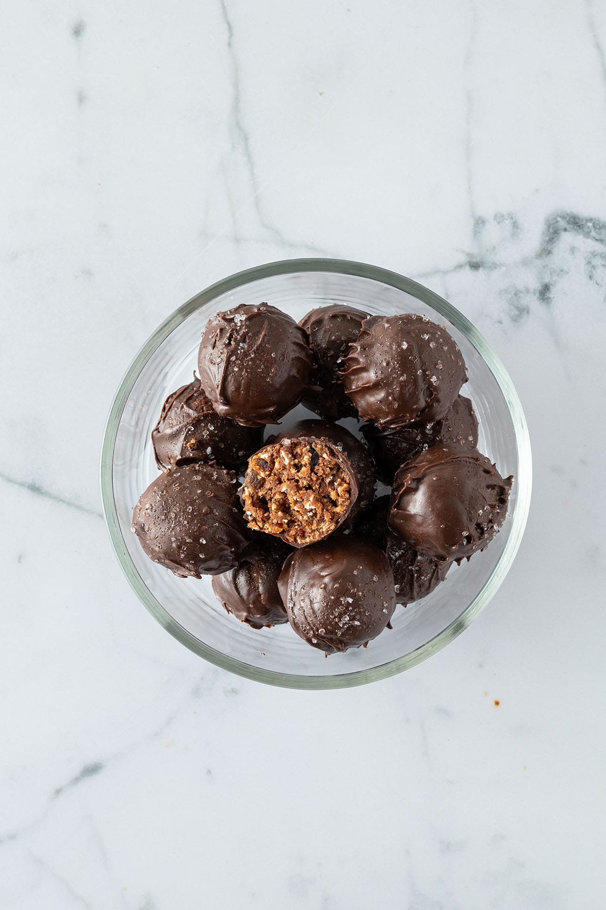Mit Schokolade &uuml;berzogene Energy Balls in einer Glas Sch&uuml;ssel.