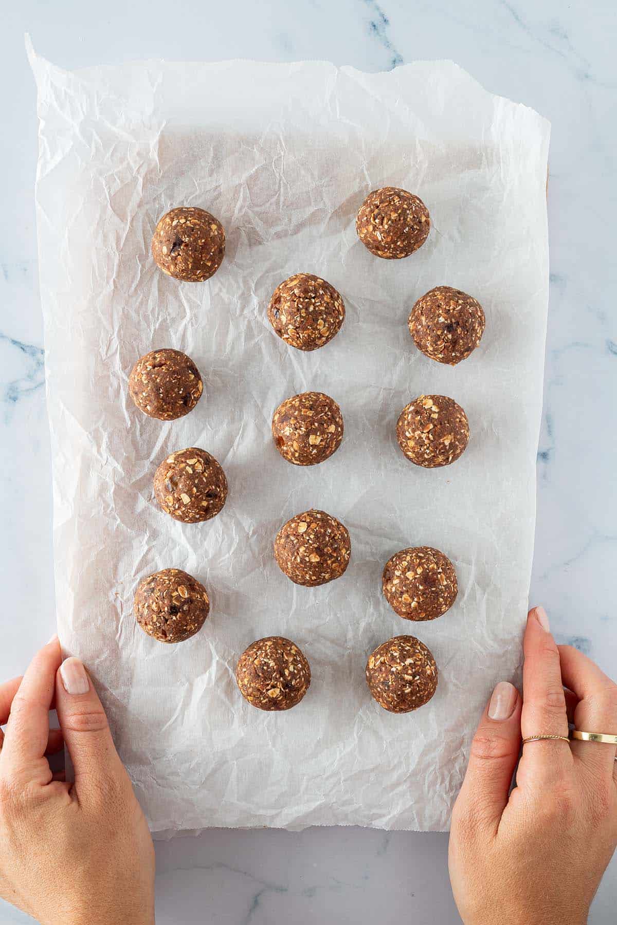 Zu runden Kugeln geformte Energy Balls auf einem St&uuml;ck Backpapier.