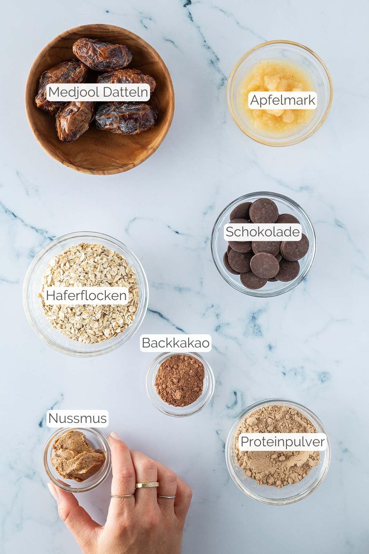 Alle Zutaten mit jeweiligen Textbeschriftungen, die f&uuml;r die Brownie Energy Balls ben&ouml;tigt werden.