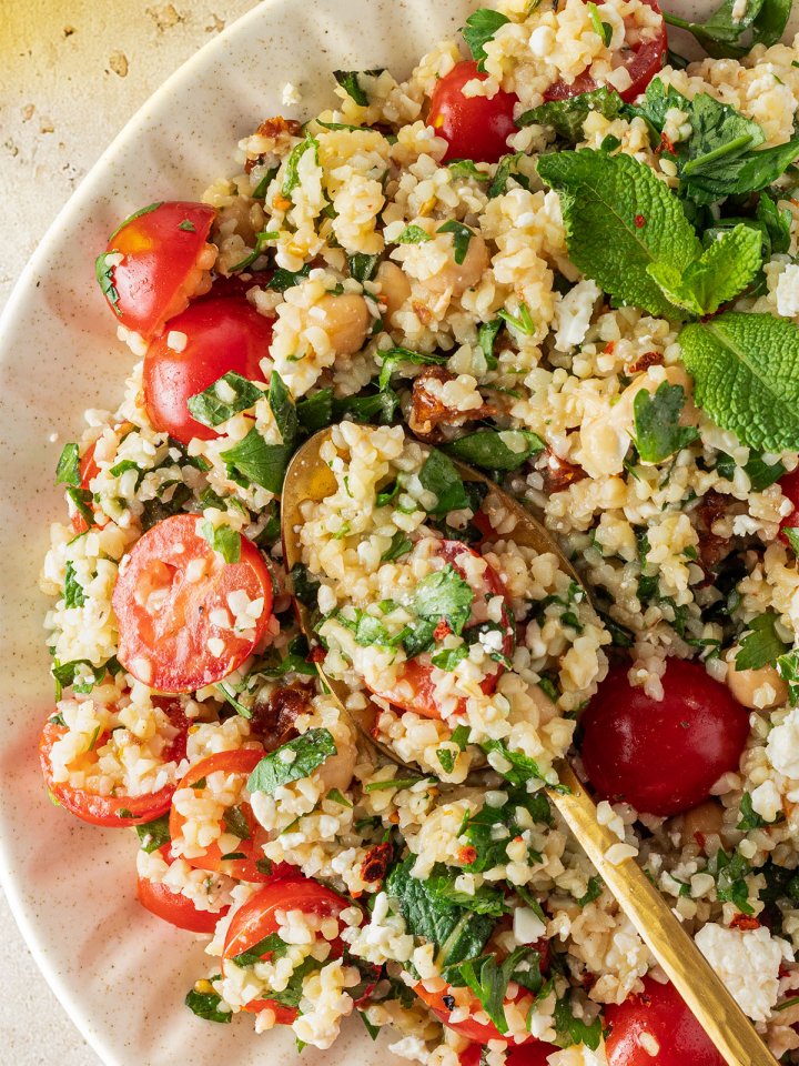 Nahaufnahme von einem Bulgur Salat mit Tomaten, Petersilie, Minze, Kichererbsen und Feta.