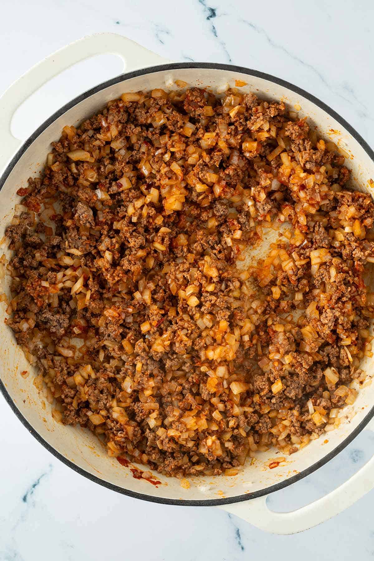 Eine gro&szlig;e Pfanne mit angebratenem Hackfleisch und Zwiebeln.