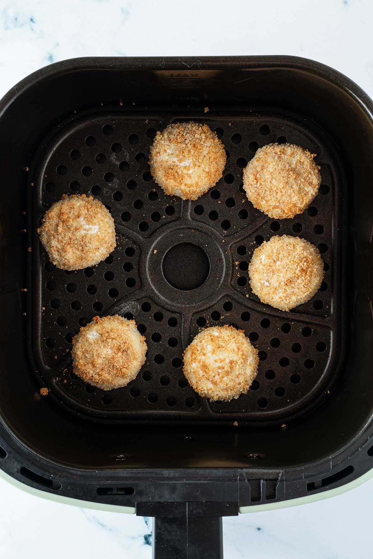 Goldbraun gebackene Mini Camemberts in dem Korb einer Hei&szlig;luftfritteuse.