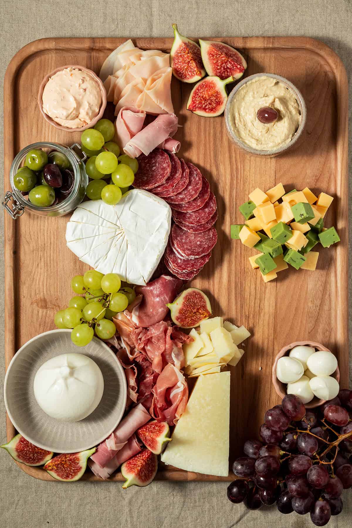 Charcuterie-Platte mit erg&auml;nzten Crackern, K&auml;sew&uuml;rfeln, Joghurt-Dip, Mozzarella-Kugeln und Trauben.