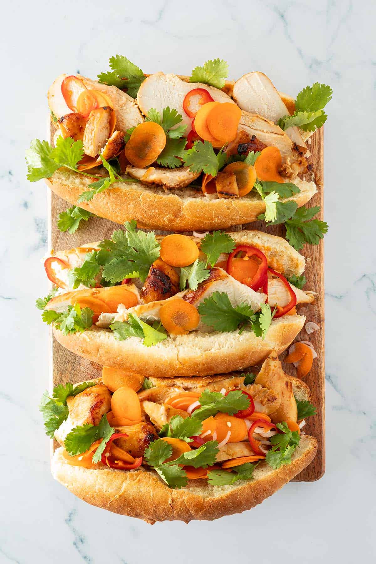rei Chicken Banh Mi Sandwiches mit H&auml;hnchen, Gem&uuml;se und Koriander auf wei&szlig;em Hintergrund.
