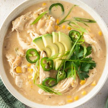 Eine Sch&uuml;ssel mit cremigen H&auml;hnchen Curry mit wei&szlig;en Bohnen, Mais, Avocado und frischen Kr&auml;utern.
