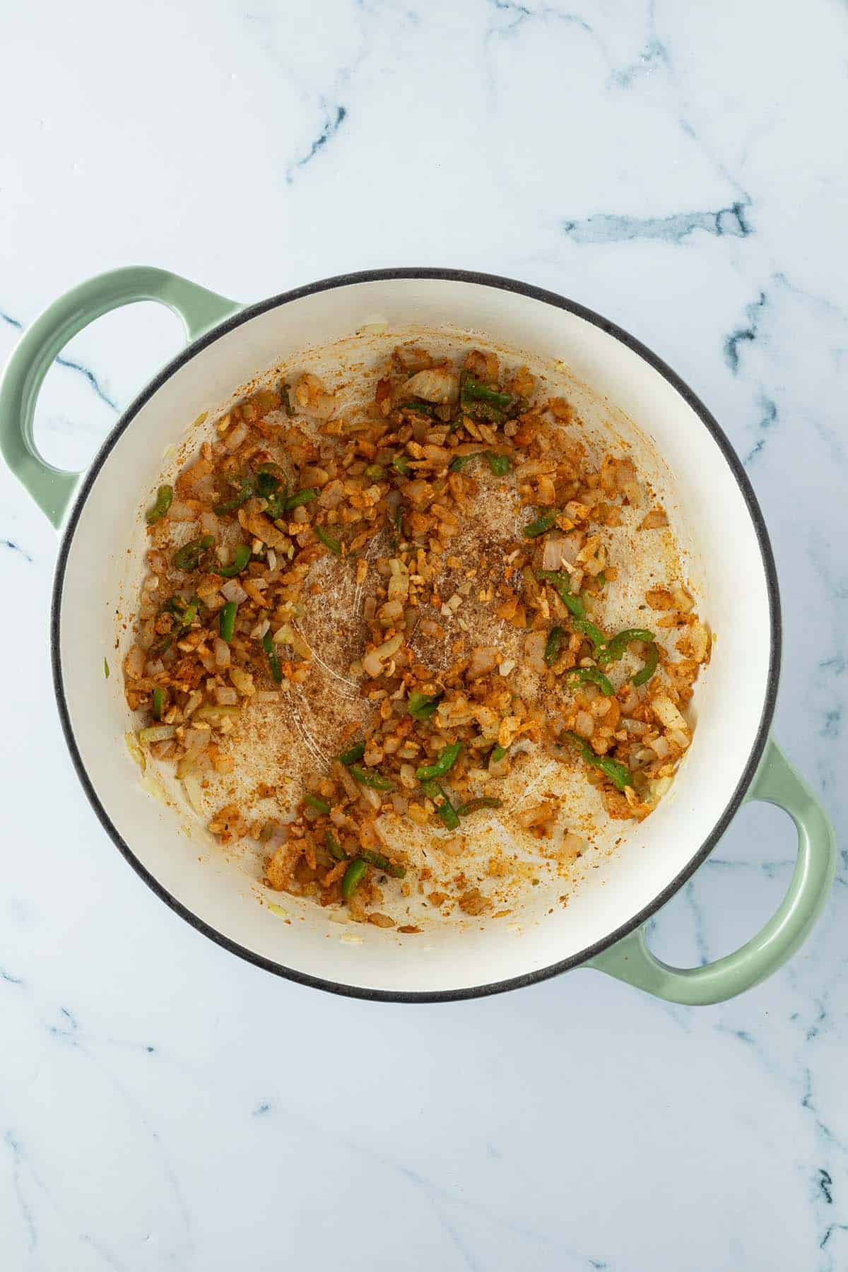 Angebratene Zwiebeln, Knoblauch, Jalape&ntilde;os und Gew&uuml;rze in einem Topf.