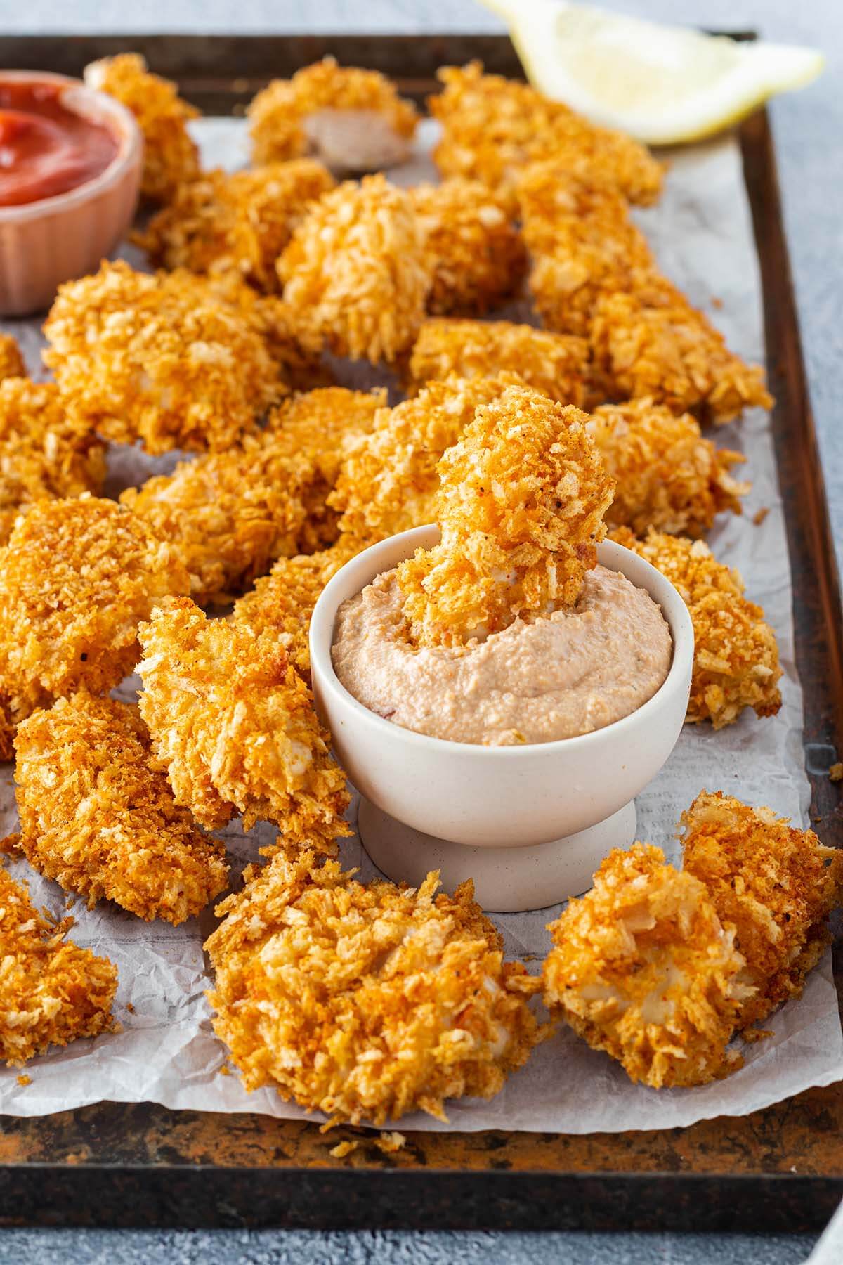 Chicken Nuggets auf einem Blech, serviert mit einem Dip, in dem ein Nugget eingetaucht wurde.
