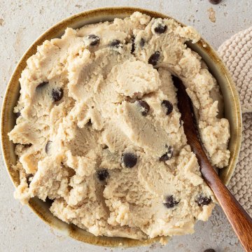 H&uuml;ttenk&auml;se Cookie Dough in einer Sch&uuml;ssel mit einem L&ouml;ffel, Deko und Schokost&uuml;ckchen im Bildrand.